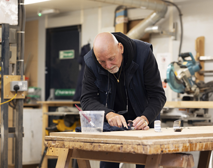 A Maintenance team member polishing brackets from the Royal Barge in the workshop.