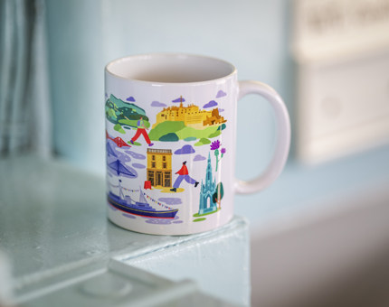 A white mug with colourful illustrations of Edinburgh on it. 