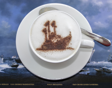 A cappuccino with a chocolate Britannia ship stencil on top.