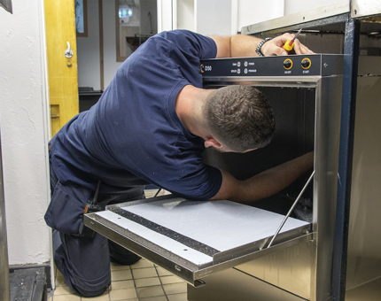 A Maintenance man fitting a dishwasher. 