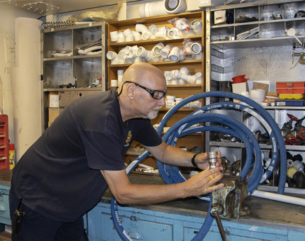 A man from the Maintenance Team examining a fuel hose. 