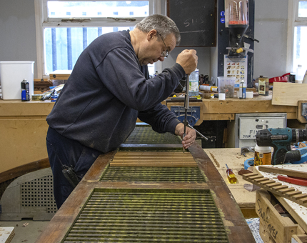 A man from the Maintenance team holding a tool to repair deck boards.