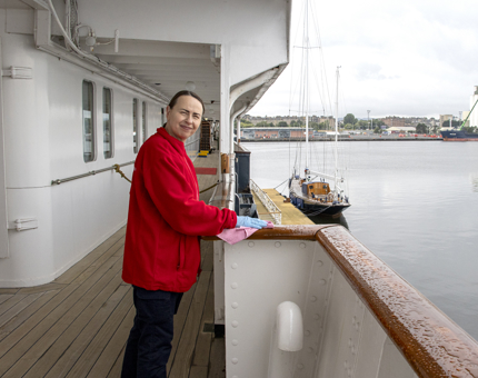 A woman in Housekeeping wipes the handrails on a rainy day. 