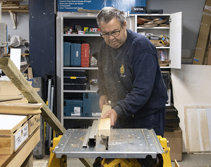 A man in the workshop cutting wood in the workshop.