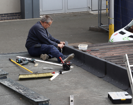The Maintenance team member attaching felt on the roof of the workshop.