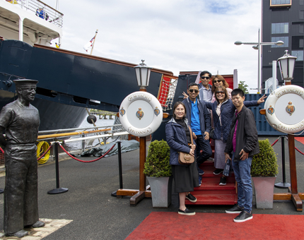 A group of six visitors stand on The Royal Yacht Britannia's Royal Brow. 