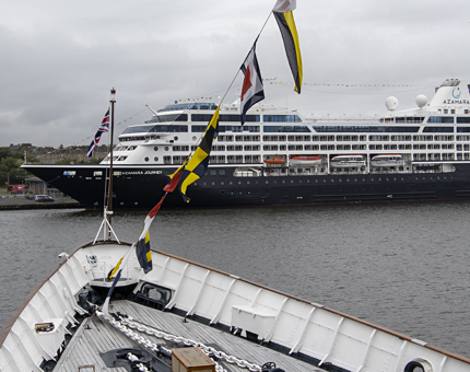 The bow of Britannia with a passenger cruise liner in the background at Leith.