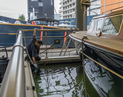 A member of the Maintenance team holds a new pond filter under the water at the Royal Barge.