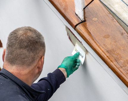 A man applies filler on the skirting plate. 