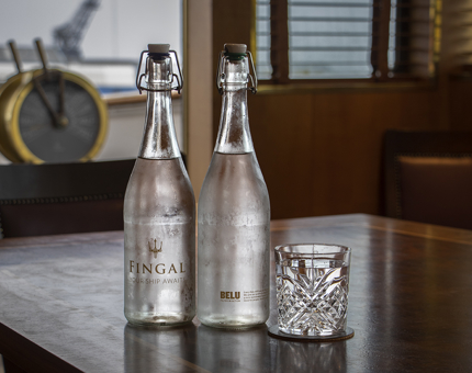 Two bottles of Fingal and Belu water and a glass in Fingal's Bridge. 