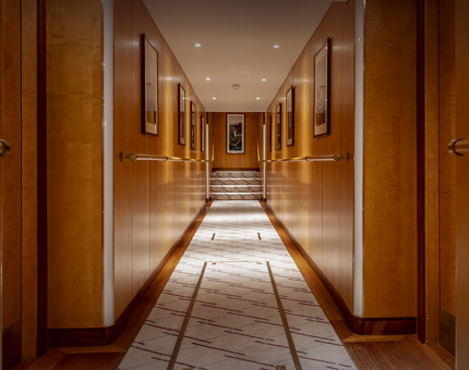 The hallway at Fingal. The walls are wooden and there black and white photographs of lighthouses on the walls. There is a cream patterned carpet on the floor.