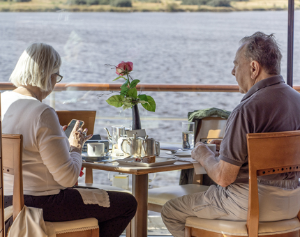 A man and woman are sitting at a table in the window of the Tearoom enjoying tea and cake.