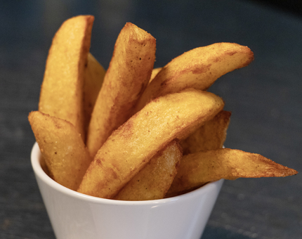 A close-up of a bowl of potato wedges. 
