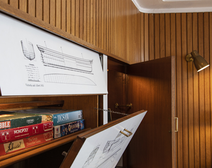 A pile of board games on a shelf in a concealed cupboard in the Sun Lounge. 