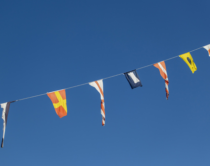 Brightly coloured dress flags flying against a blue sky. 