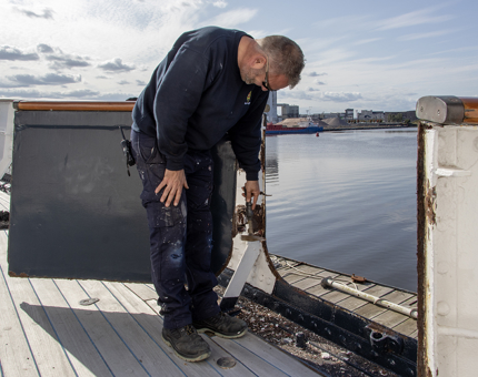 A member of the Maintenance Team tightens a bolt on the Fast Motor Launch. 