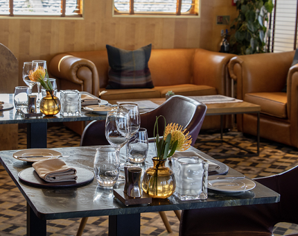 A dining table in Fingal's Lighthouse Restaurant & Bar. Tan leather sofas with tweed cushions are in the background. 