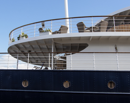 The exterior of Fingal with the Lighthouse Restaurant and Bar's outdoor deck. There are chairs, tables and planters filled with flowers. 