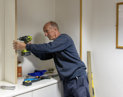 A member of the Facilities Team drills into a panel of wood as he created pigeonholes in the new Duty Managers' office.