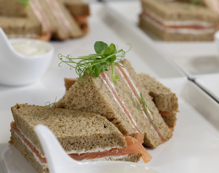Plates of smoked salmon and cream sandwiches on wholemeal bread. 