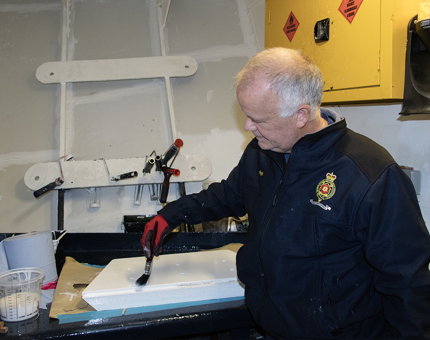 A man painting boards with white paint in the workshop. 