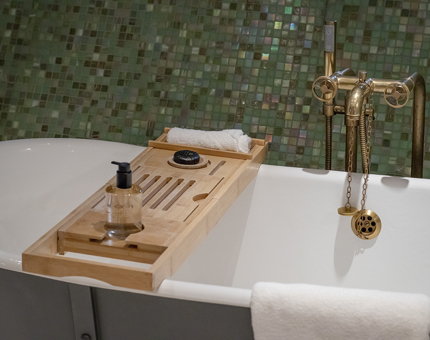 A cabin bathroom with a roll-top bath and tray holding a shower gel, flannel and bar of soap. 