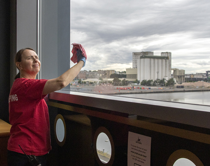 Housekeeper, Renata, polishing the glass window in the Visitor Centre.