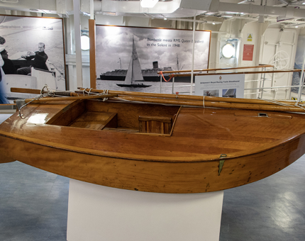 Queen Elizabeth II received this pram dinghy, Tui, during a Royal visit to New Zealand in 1953. Tui is kindly on loan from Portsmouth Naval Base Property Base.
