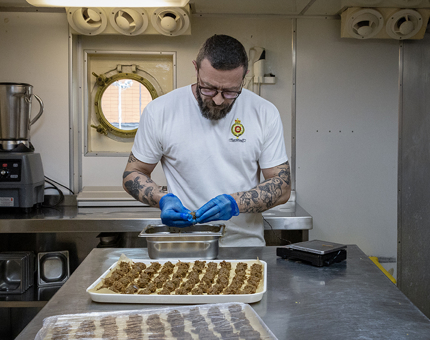 A Chef preparing duck canapes in the Galley. 