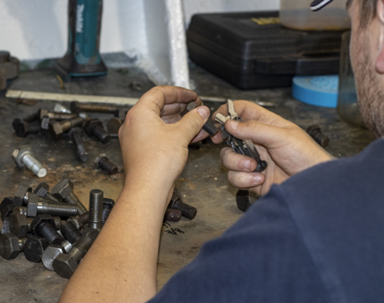 A member of the Maintenance team checking nuts and bolts in a workshop.