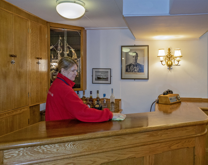 A Housekeeper polishing the bar in Britannia's Wardroom. 