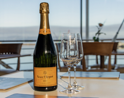A bottle of Champagne and two flutes are on a table in the Royal Deck Tearoom. 