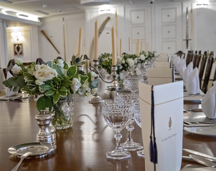 The State Dining Room table on Britannia is set for the evening with menus, silver candelabra and white floral displays. 