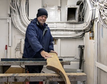 A member of the Maintenance Team sanding a handrail.