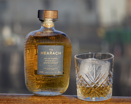 A bottle of The Hearach whisky with a tumbler full next to it. 