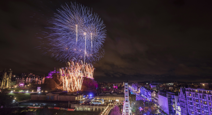 Edinburgh Castle at night on Hogmanay. There are brightly coloured fireworks in the sky. 