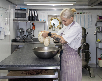 A Pastry Chef making sourdough bread in a bowl in the onboard Galley.
