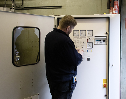An electrician from the Maintenance Team checking gauges on a board.