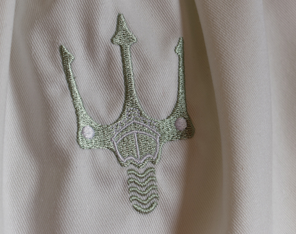 The detail of Fingal's trident logo, embroidered in gold thread on a slippers bag.