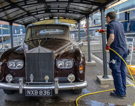 A member of the Facilities Team washing the Rolls Royce on the Quayside. 