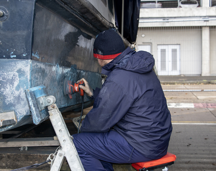 A man from the Maintenance Team sanding the Fast Motor Launch.