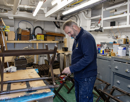 A member of the Maintenance Team varnishing a luggage rack. 