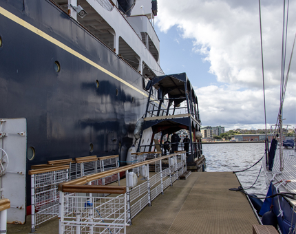 The paint cat pontoon next to the side of the Yacht. Maintenance Team members are working on it painting the hull.