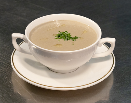 A bowl of mushroom soup sitting on a saucer. 