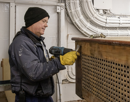 A man removing the old varnish off the rope box.