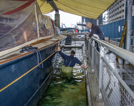 Members of the Maintenance Team beginning work to pump out water next to the Royal Barge.