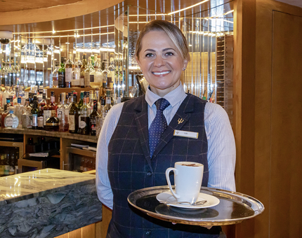 A Waiter in Fingal's Lighthouse Restaurant & Bar holding a tray with a coffee.