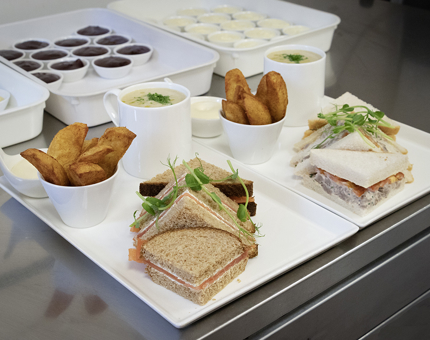 Two white platters with a mug of soup each and sandwiches