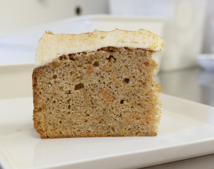 A large slice of carrot cake on a white plate.