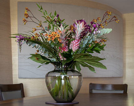 A tall vase of pink and orange flowers on the dining table in the Skerryvore Suite. 